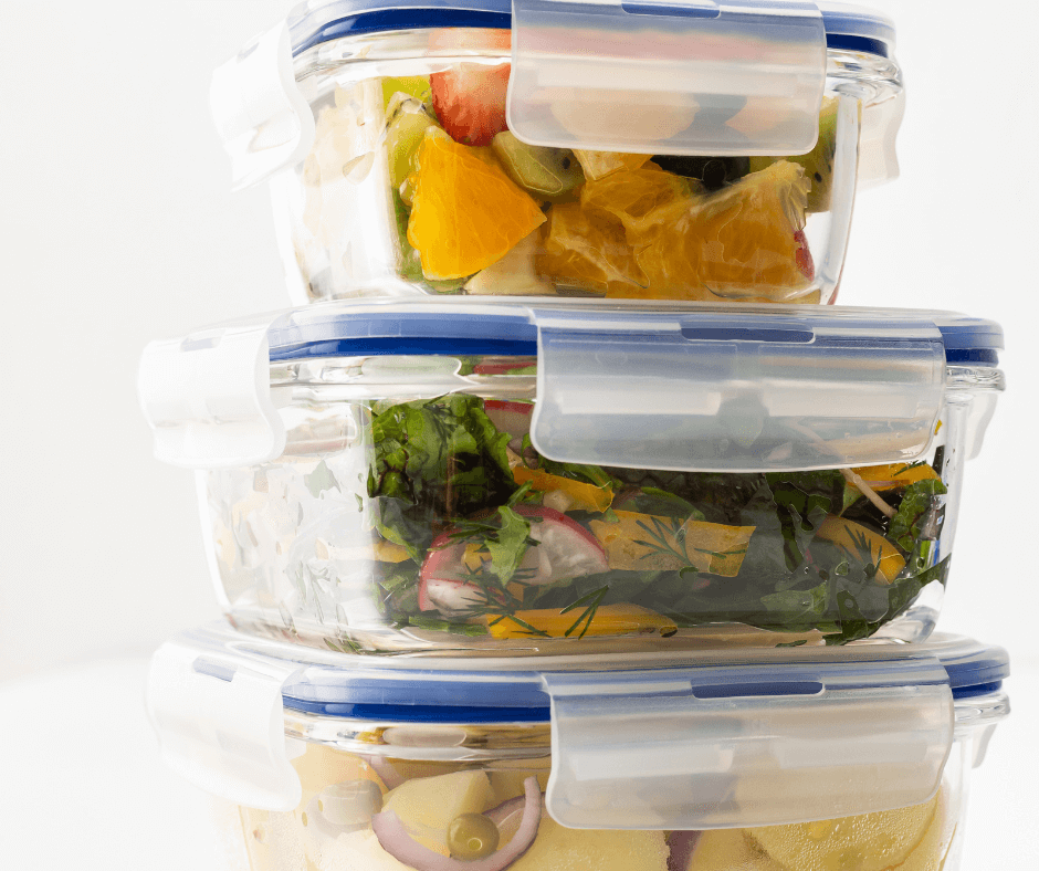 A stack of glass containers with lids filled with leftover food.