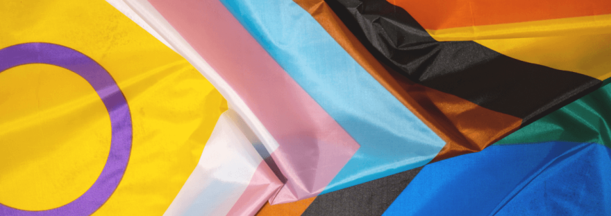 Laying flat and grouped together are the intersex, transgender, and progress Pride flags; photo via yanishevska/Canva.