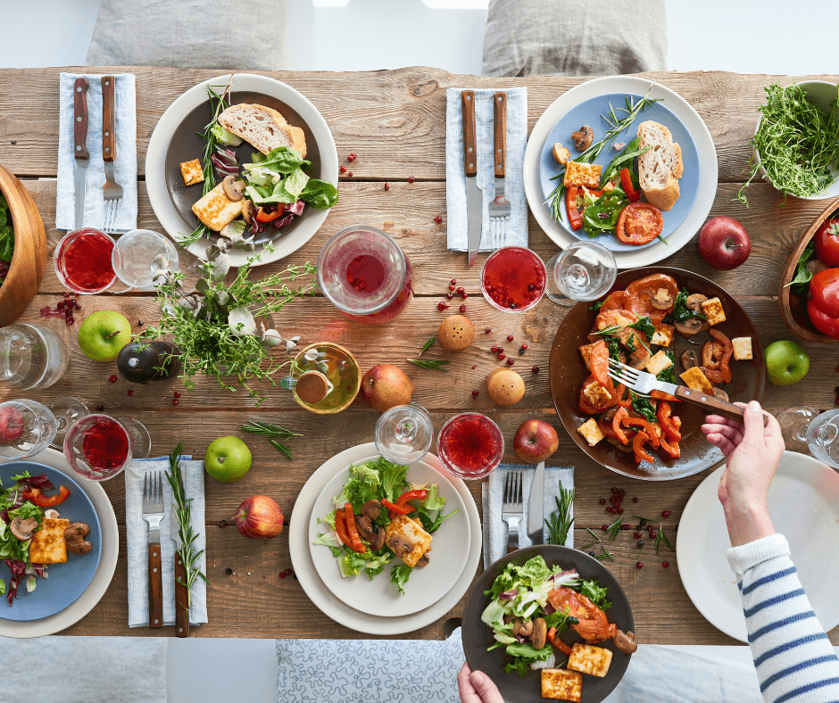 A top view of a dining table set for dinner with each plate filled with a variety of delicious vegan food.